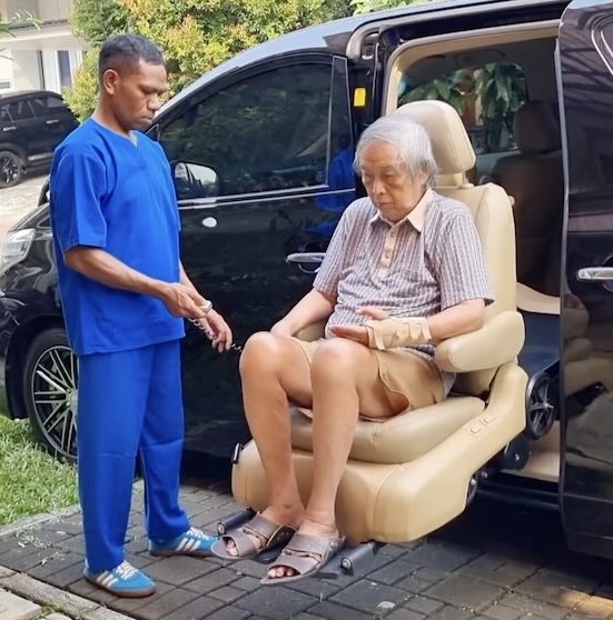 Perawat TransCare mendampingi pasien lansia di dalam kendaraan medis menuju rumah sakit